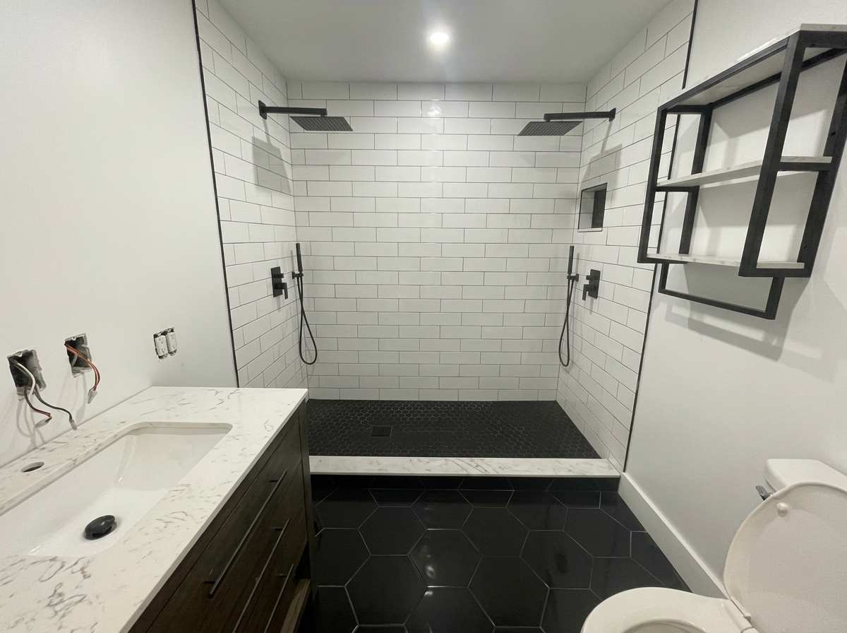 Double-shower bath with subway tile and black hex floor